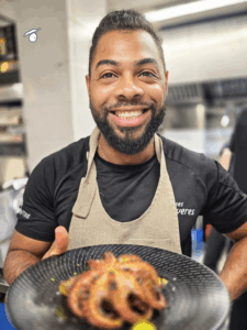 Camarero sonriente presenta plato con pulpo