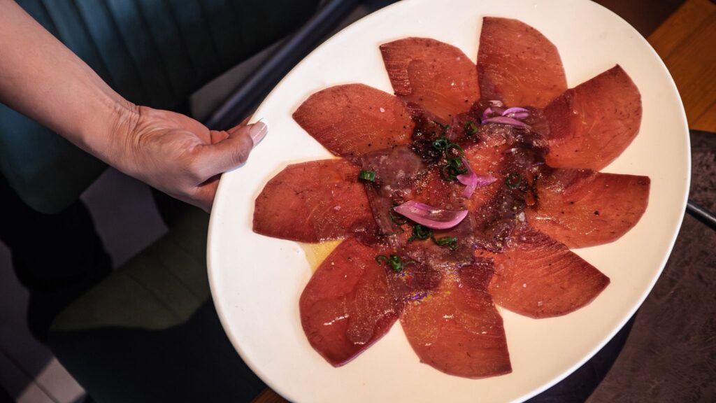 Carpaccio de atún rojo servido en plato blanco y plano