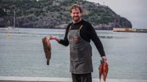 Persona al lado del mar mostrando su captura de pesca a la cámara