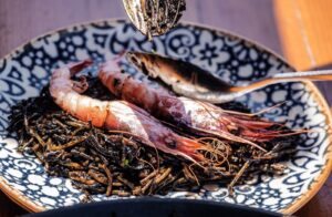 Fideuá negra con gambas de Sóller y mejillones servida en plato hondo en Ses Oliveres Port de Sóller.