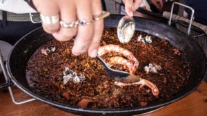 Arroz seco dentro de su paellera con gambas rojas y sepia