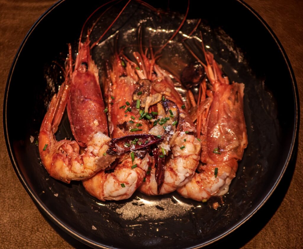 Carabineros al ajillo presentados en un plato de cerámica oscura