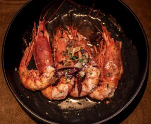 Carabineros al ajillo presentados en un plato de cerámica oscura
