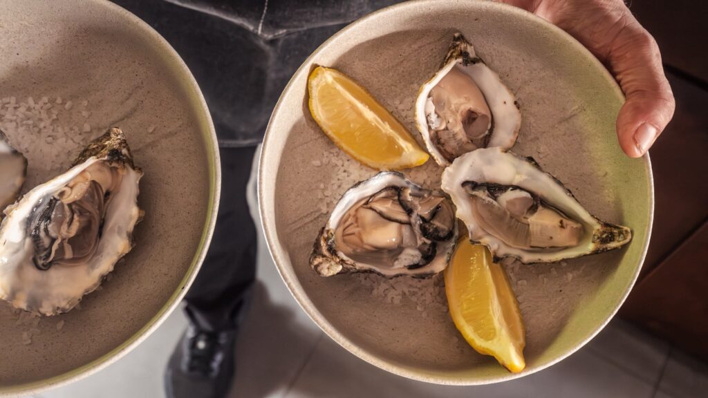 Ostras frescas servidas con limón sobre sal gruesa en Ses Oliveres Port de Sóller, restaurante con terraza frente al Mediterráneo.